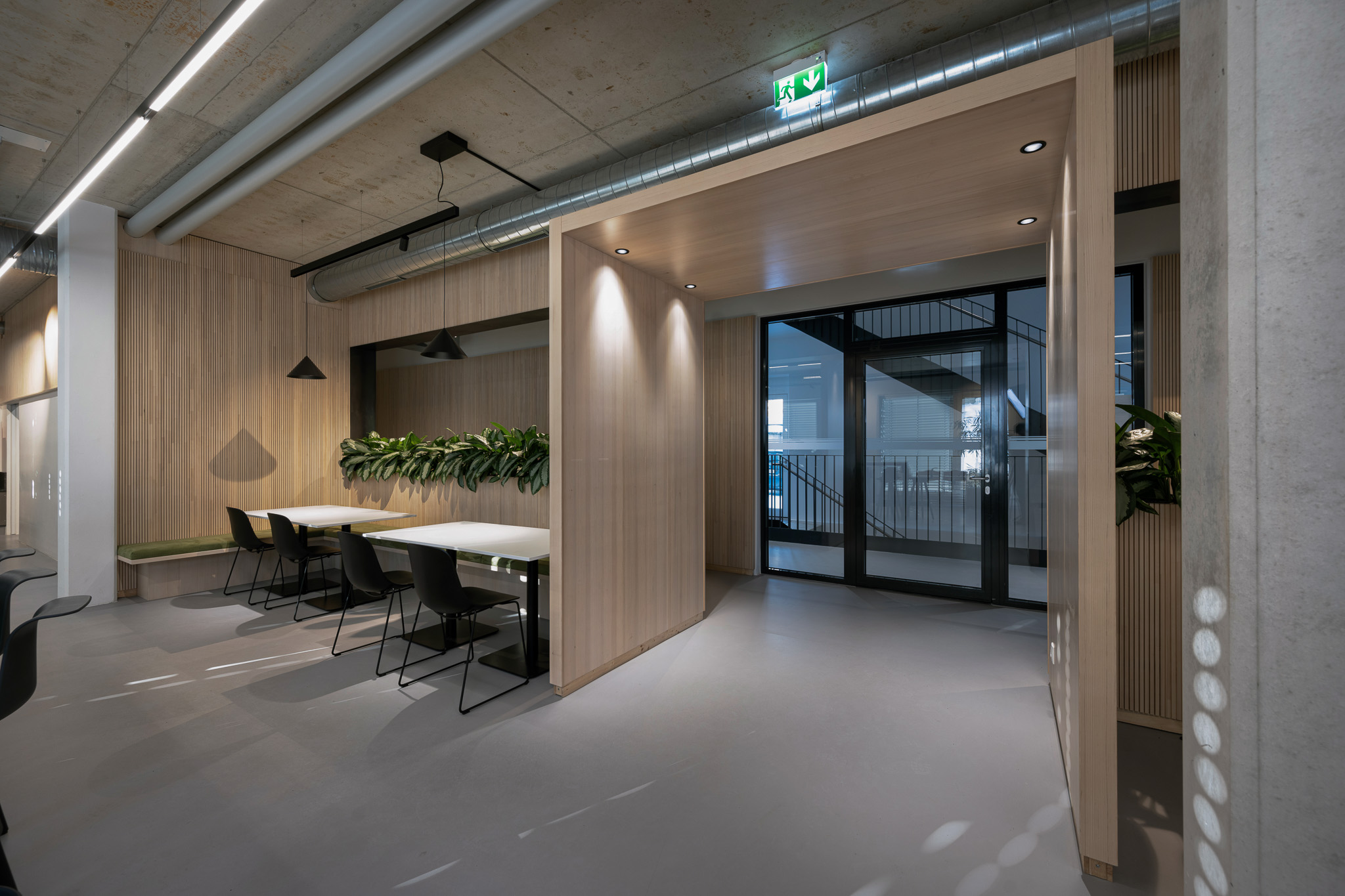 Ein modernes Büro im Industrialstyle kann eine einzigartige und inspirierende Umgebung bieten. Die Kombination von Glas, Metall, Holz und Beton verleiht dem Raum einen zeitgemäßen Look, während Mooswände und Pflanzen für eine angenehme Atmosphäre sorgen. Um den Industrialstyle in einem Büro umzusetzen, wurde mit offenen Grundrissen gearbeitet, um die Räume luftig und großzügig wirken zu lassen. Große Glasfenster und Trennwände aus Glas ermöglichen viel Tageslicht. Metallische Elemente wie Stahlträger oder -regale können als Blickfang dienen und dem Raum einen industriellen Charme verleihen. Holz ist ein weiteres wichtiges Element im Industrialstyle. Es wurde für Böden, Möbel und Wandverkleidungen verwendet, um Wärme und Natürlichkeit in den Raum zu bringen. Eine Kombination von Holz und Metall wirkt besonders ansprechend und schafft einen Kontrast zwischen organischen und industriellen Elementen. Bei der Ausführung eines modernen Büros ist es wichtig, eine Balance zwischen funktionalen Aspekten und ästhetischem Design zu finden. Die Wahl der richtigen Möbel, Beleuchtung und Farben komplettiert den Raum und schafft eine angenehme Arbeitsumgebung, in der Mitarbeiter sich wohlfühlen und kreativ arbeiten können.